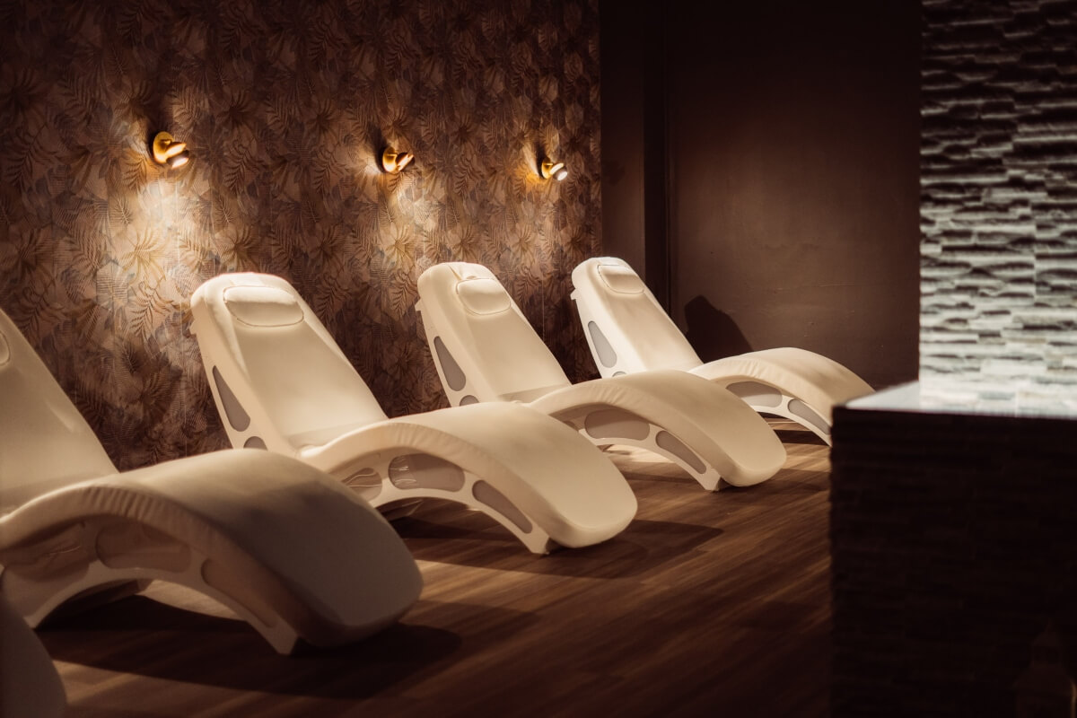 Four white lounge chairs in a dimly lit relaxation room.